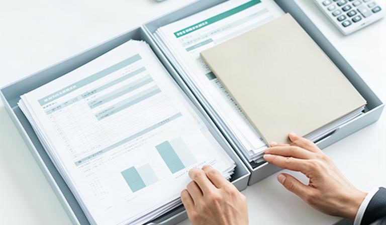 担当者が採用候補者の問い合わせ記録と人事分析用の集計資料を分けて確認するデスク上の風景